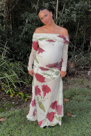 Pregnant woman in Mama Rentals By Nicola Belle Maxi Dress in Bordeaux Floral standing outdoors with greenery in the background.