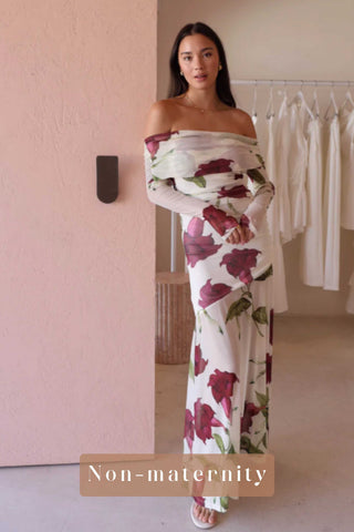 A non-pregnant woman wearing the By Nicola Belle Maxi Dress in Bordeaux Floral in a clothing store.