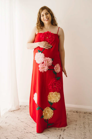 A pregnant lady wearing the Mama Rentals Elliatt Buttercup Embroidered Maxi Dress in a studio.