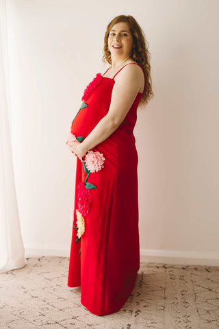 A pregnant lady wearing the Mama Rentals Elliatt Buttercup Embroidered Maxi Dress in a studio.