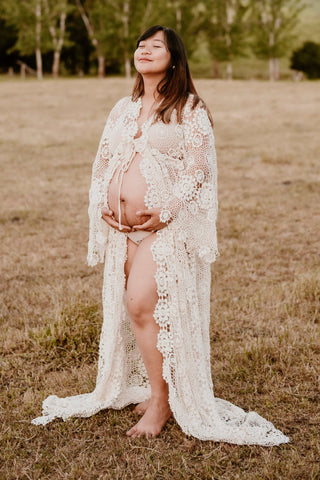 Bumpshoot of a lady wearing a boho lace crochet robe, the Mama Rentals Elvira Crochet Robe