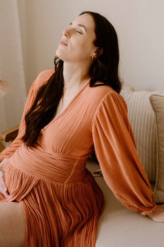 A pregnant woman wearing the Mama Rentals Jen's Pirate Booty Lapis Maxi Dress - Rust in a studio.