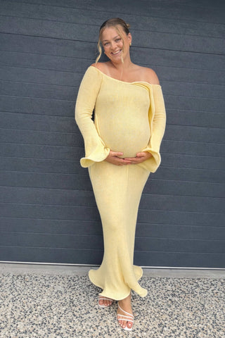 A pregnant lady wearing the Meshki Sandrine Off Shoulder Knit Maxi Dress in Lemon at her baby shower.