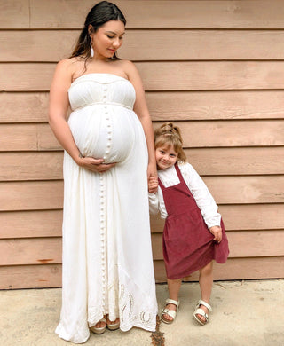 A pregnant lady wears Mama Rentals' Fillyboo "Zippora" Strapless Maternity Maxi Dress - Vanilla Cream with her daughter.
