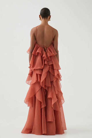 Close-up side view of woman wearing the Aje Pandorea Layered Maxi Dress in Coral Clay, featuring halter neckline and cascading ruffle details.