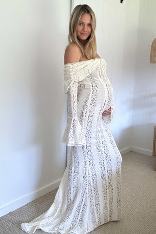 Pregnant lady wearing House of CB Belle Vintage Cream Floral Lace Off Shoulder Maxi Dress in a room with a plain wall.