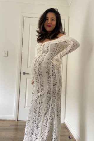 Woman wearing a lace dress standing in a room with white walls and a door.