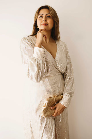 A woman wearing the Mama Rentals Jasmine Sequin Gown - Champagne holding the Olga Berg Quinn Woven Gold Clutch in a studio.