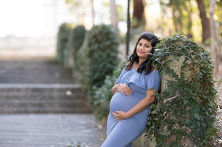 A beautiful pregnant lady wears Mama Rentals Isabel Off the shoulder ruffle maternity dress in dusty blue at her maternity shoot.